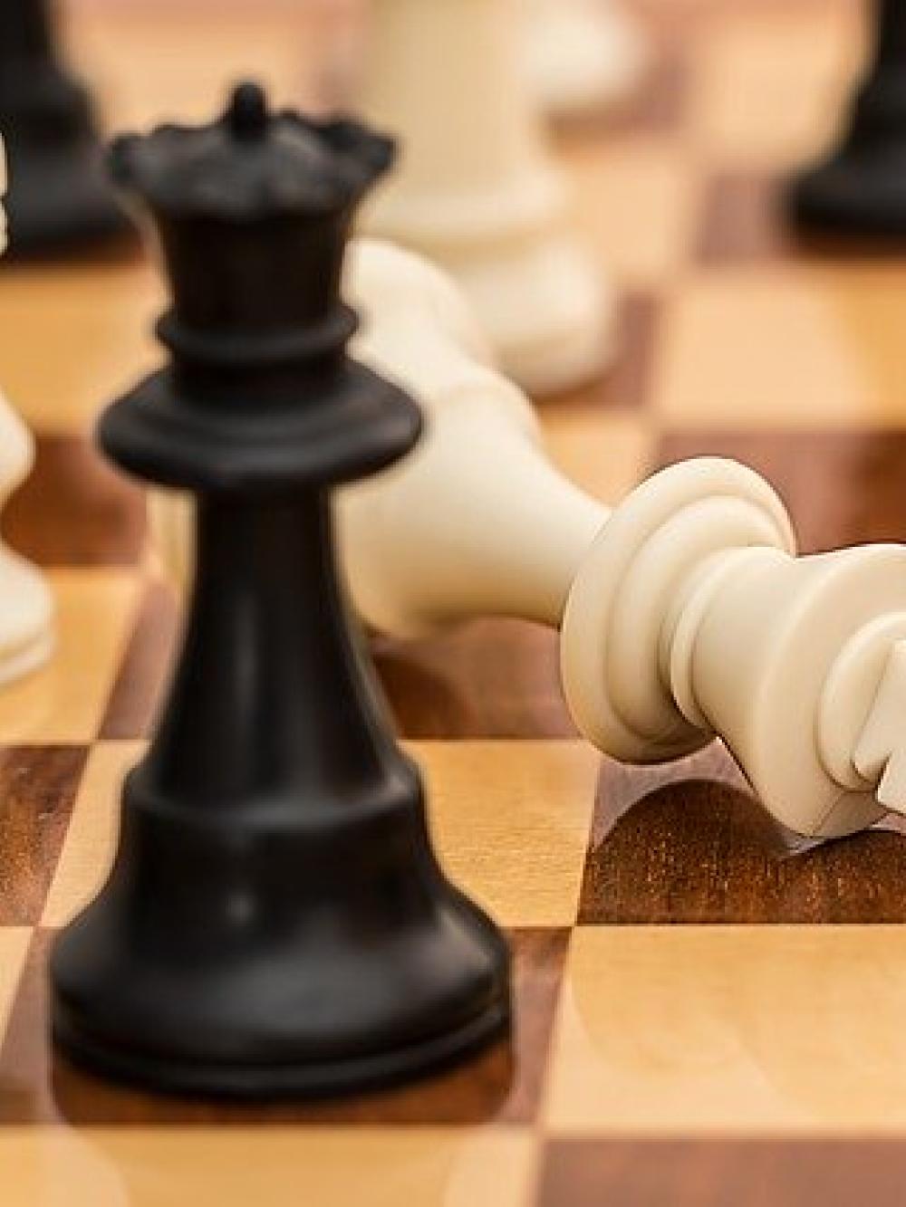 close up of a chessboard and the white king has been knocked over accepting defeat